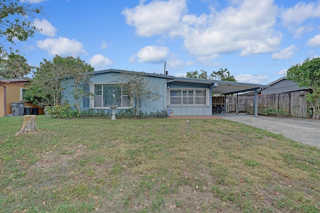 view of front of home featuring stucco siding, a front yard, fence, a carport, and driveway