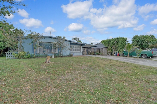 view of front of house with a carport, driveway, a front lawn, and fence