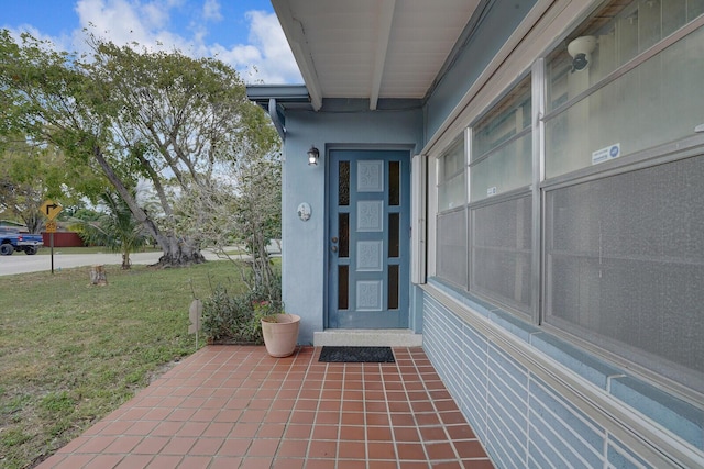 property entrance featuring a lawn and stucco siding