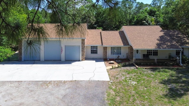 view of front facade with an attached garage, covered porch, concrete driveway, stone siding, and stucco siding