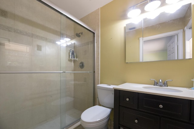 full bathroom with vanity, a shower stall, and toilet