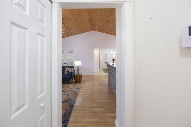 hall featuring light wood-type flooring, lofted ceiling, and wooden ceiling