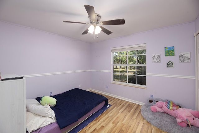 bedroom featuring ceiling fan, baseboards, and wood finished floors