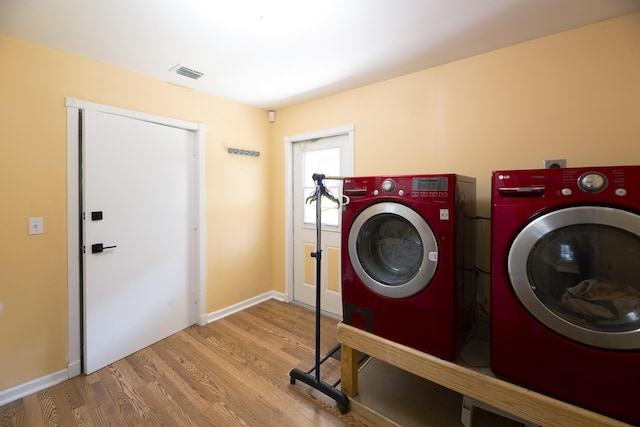 laundry room with laundry area, wood finished floors, visible vents, baseboards, and washer and dryer