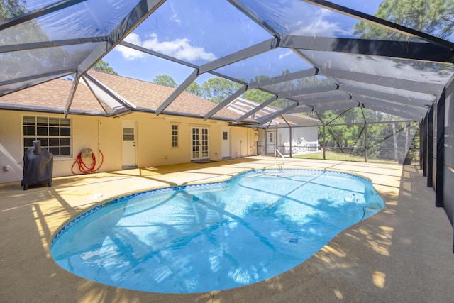 outdoor pool with glass enclosure, french doors, and a patio