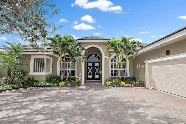 property entrance with french doors, decorative driveway, a tile roof, and stucco siding