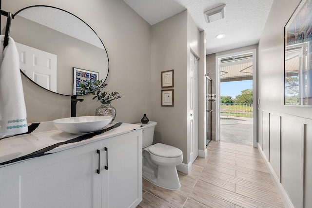 full bathroom with visible vents, toilet, a stall shower, a textured ceiling, and vanity