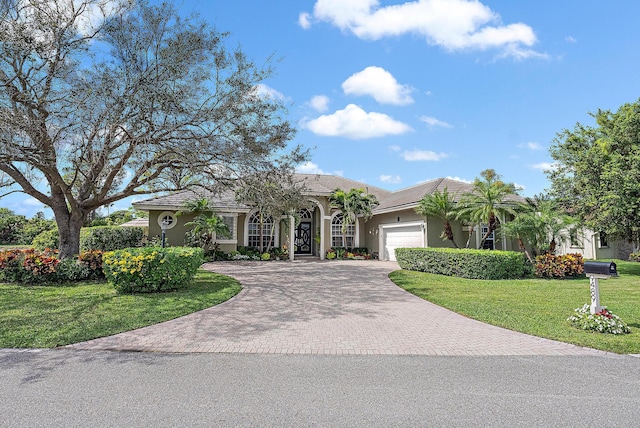 view of front of house featuring a garage, decorative driveway, a front yard, and stucco siding