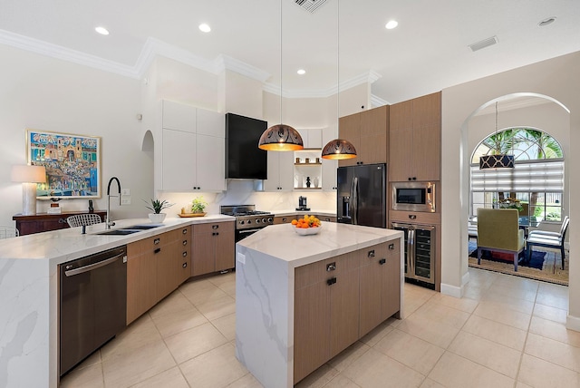 kitchen with beverage cooler, a peninsula, ornamental molding, a sink, and appliances with stainless steel finishes