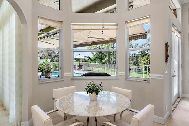 dining room featuring light tile patterned floors, baseboards, and arched walkways