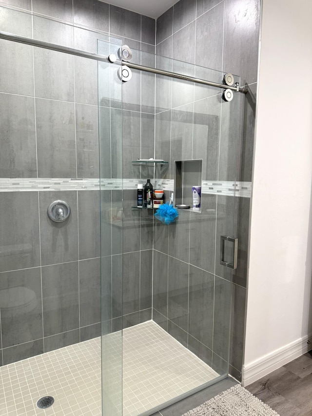 bathroom with a shower stall, baseboards, and wood finished floors