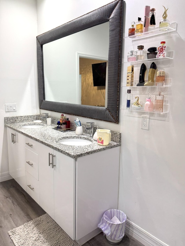 bathroom with double vanity, a sink, and wood finished floors