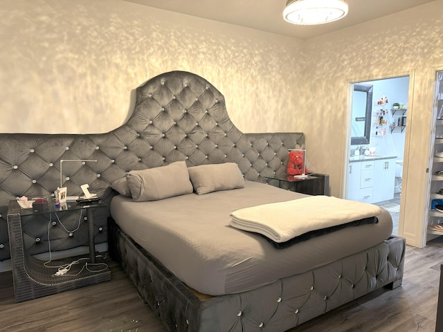 bedroom featuring wood finished floors, connected bathroom, and wallpapered walls