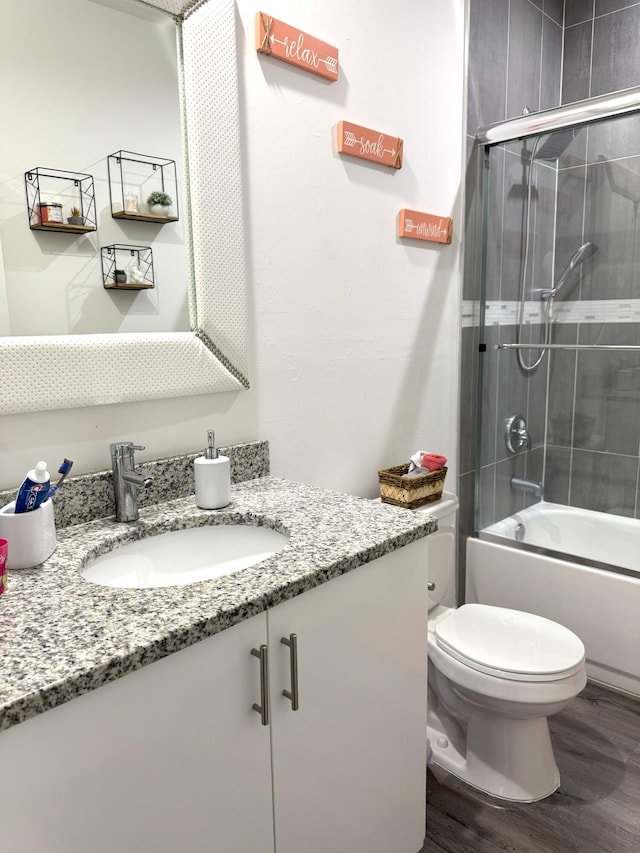 bathroom with toilet, enclosed tub / shower combo, wood finished floors, and vanity