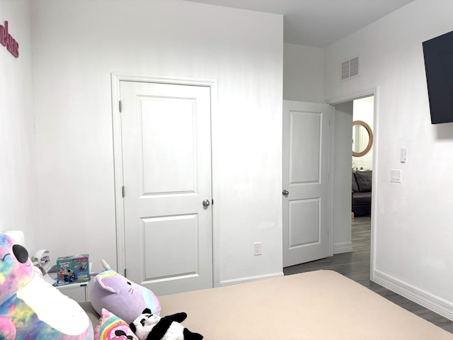 bedroom featuring wood finished floors, visible vents, and baseboards