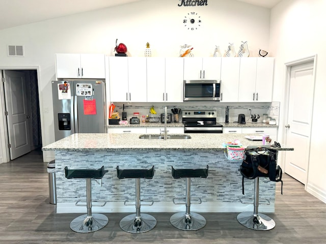 kitchen featuring visible vents, appliances with stainless steel finishes, white cabinets, and a breakfast bar area