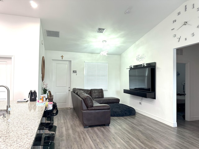 living area featuring wood finished floors, visible vents, and baseboards