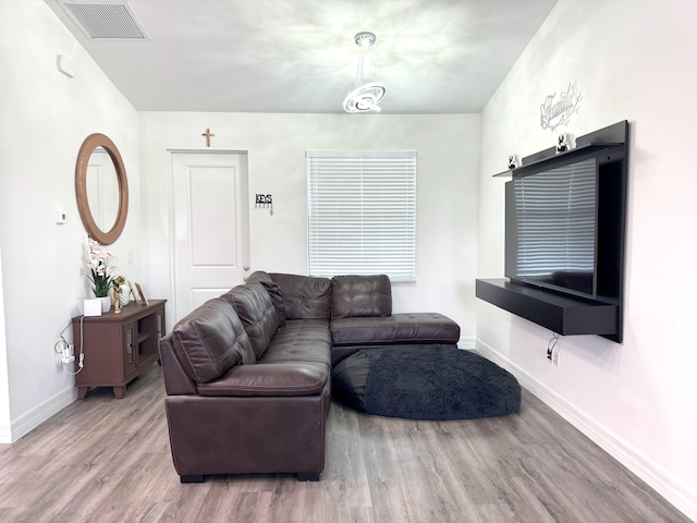 living room featuring baseboards, visible vents, and wood finished floors