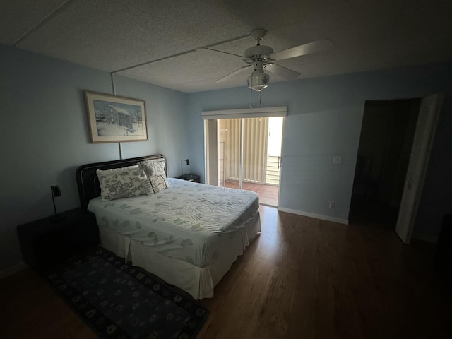 bedroom featuring access to exterior, a ceiling fan, baseboards, and wood finished floors