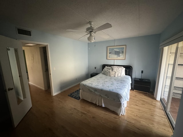 bedroom featuring a ceiling fan, a textured ceiling, visible vents, and wood finished floors