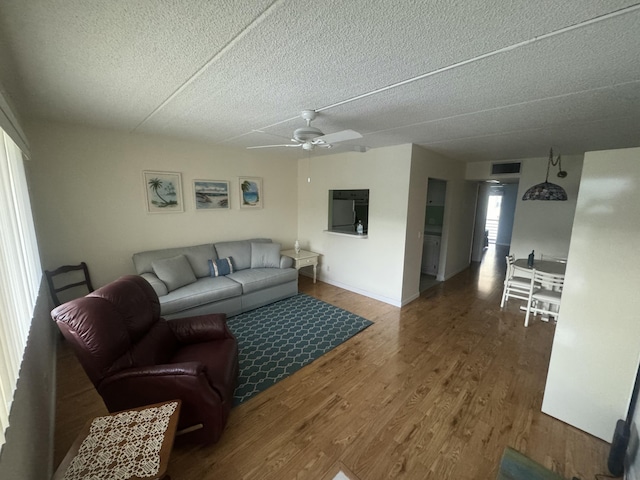 living area featuring visible vents, ceiling fan, a textured ceiling, wood finished floors, and baseboards