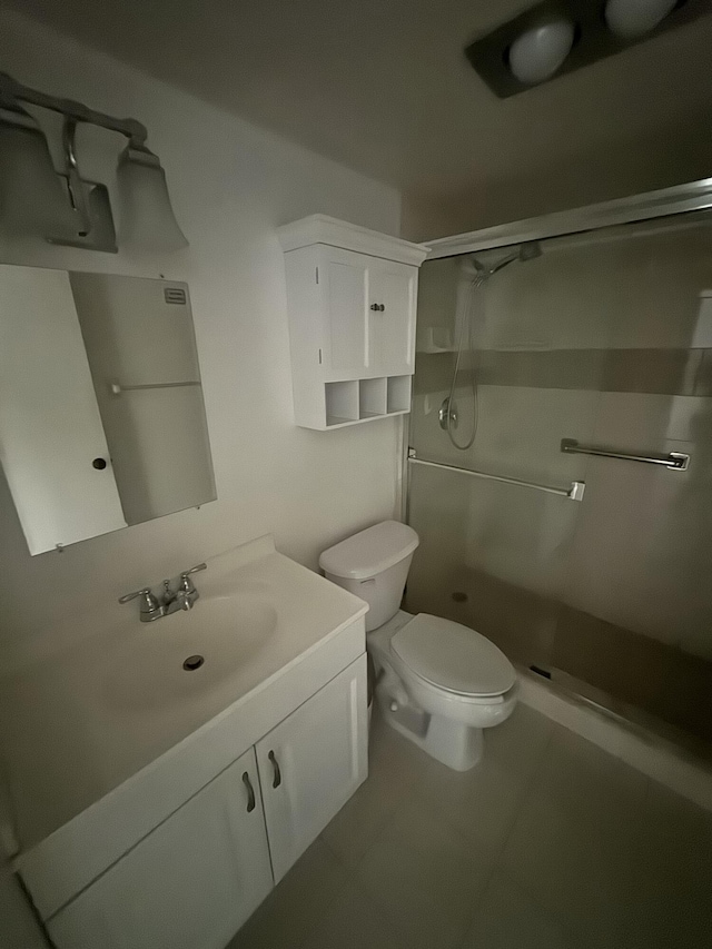 bathroom with tile patterned floors, vanity, toilet, and a stall shower