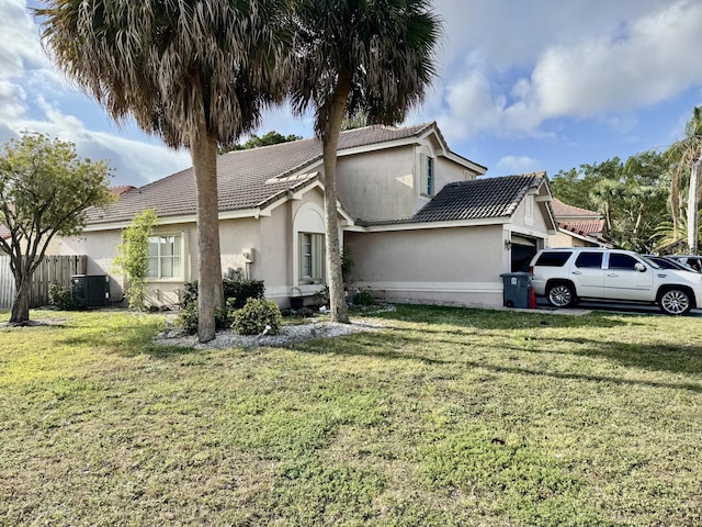 view of side of property featuring a garage, fence, a tiled roof, a lawn, and stucco siding