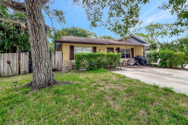 single story home featuring fence, a front lawn, a patio, and stucco siding