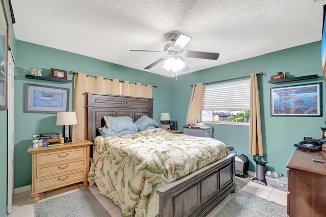 bedroom featuring light tile patterned floors, baseboards, a ceiling fan, and a textured ceiling