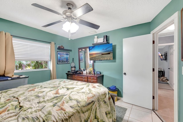 bedroom featuring light tile patterned floors, ceiling fan, visible vents, and a textured ceiling