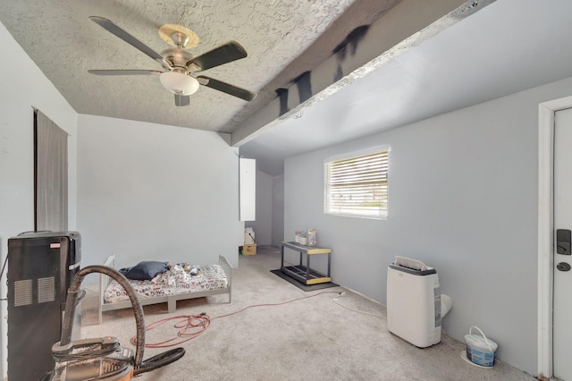 interior space with carpet, beam ceiling, ceiling fan, and a textured ceiling