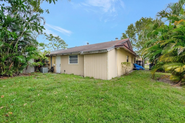 rear view of property featuring a lawn and central air condition unit