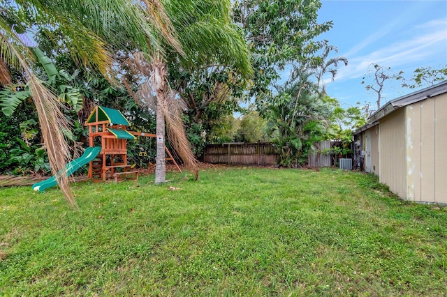 view of yard with central AC, fence, and a playground