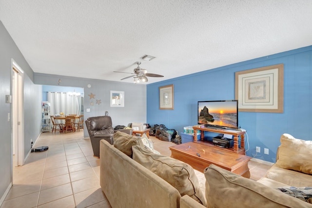 living area with visible vents, light tile patterned flooring, ceiling fan, a textured ceiling, and baseboards