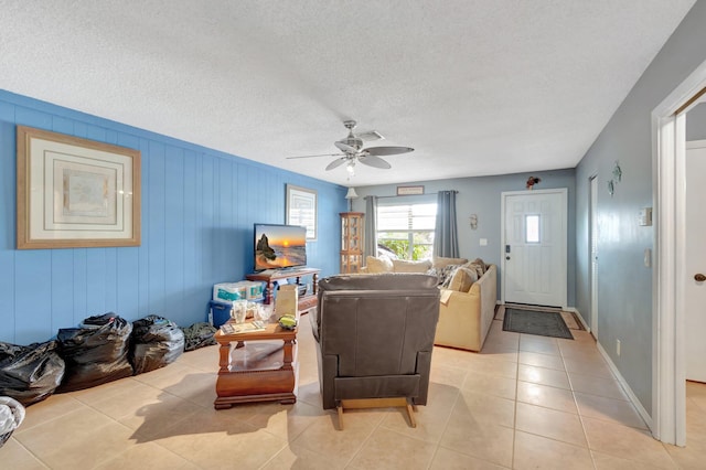 living area featuring light tile patterned floors, a ceiling fan, and a textured ceiling