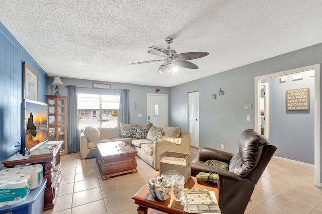 living room with a ceiling fan, a textured ceiling, and light tile patterned floors