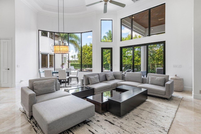 living room featuring marble finish floor, a high ceiling, ornamental molding, a ceiling fan, and baseboards