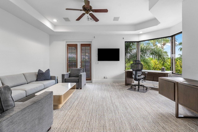 living room with a raised ceiling, visible vents, and baseboards