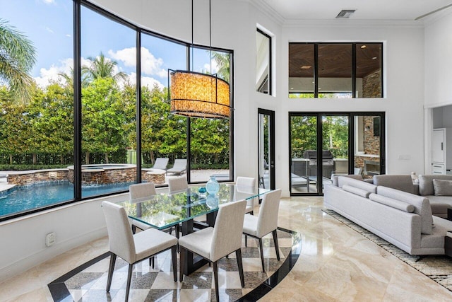 dining area featuring baseboards, a high ceiling, visible vents, and crown molding