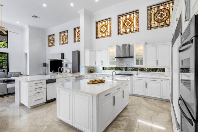 kitchen featuring marble finish floor, wall chimney range hood, a towering ceiling, and a peninsula