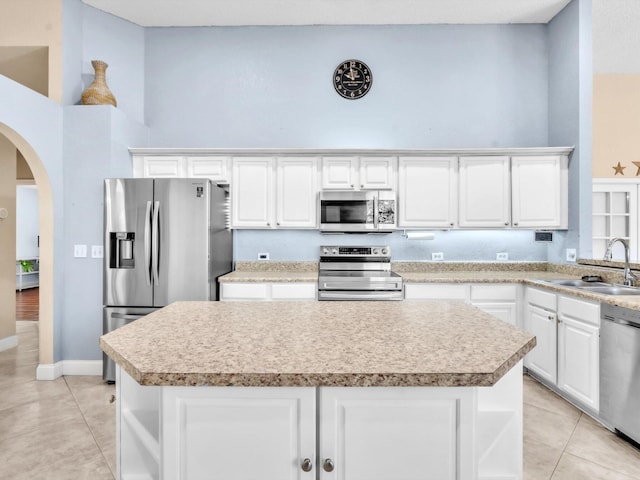 kitchen with appliances with stainless steel finishes, open shelves, a sink, and a center island