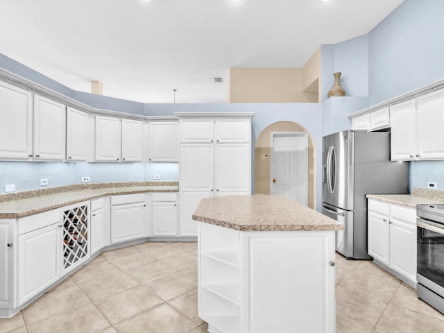 kitchen with light tile patterned floors, light countertops, appliances with stainless steel finishes, white cabinetry, and a kitchen island