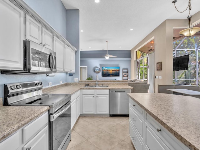 kitchen with a sink, white cabinets, open floor plan, light countertops, and appliances with stainless steel finishes