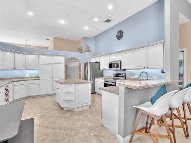 kitchen with stainless steel appliances, a high ceiling, a peninsula, visible vents, and open shelves