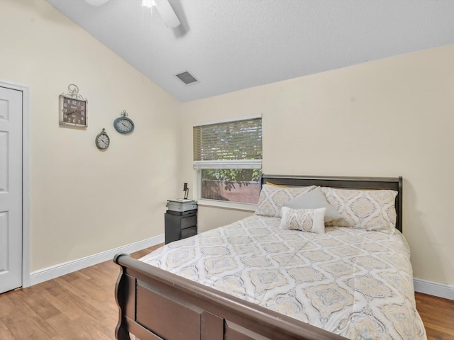 bedroom with visible vents, ceiling fan, vaulted ceiling, wood finished floors, and baseboards