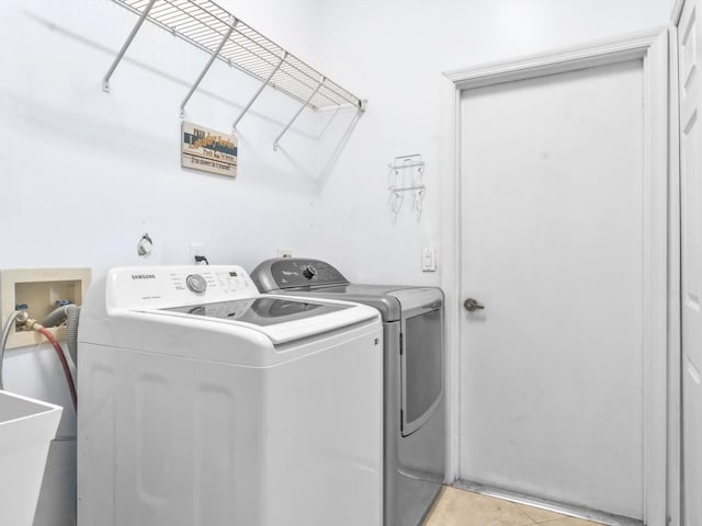 clothes washing area with laundry area, washing machine and dryer, and light tile patterned floors