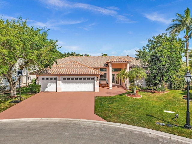 mediterranean / spanish-style home featuring an attached garage, a tiled roof, driveway, stucco siding, and a front lawn