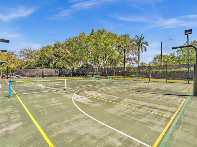 view of sport court featuring a tennis court and fence