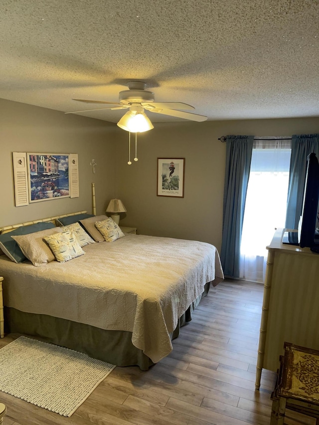 bedroom featuring a textured ceiling, ceiling fan, and wood finished floors