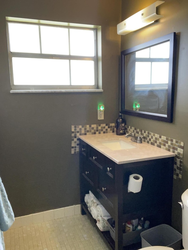 half bathroom with toilet, tile patterned floors, tasteful backsplash, and vanity